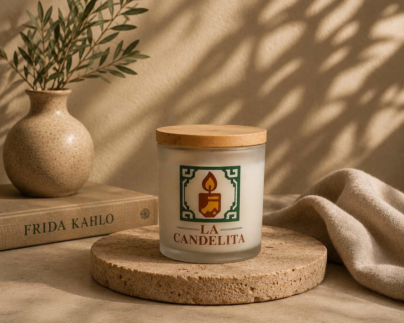 A frosted glass jar candle with a bamboo lid sits on a round stone coaster. The candle features a green and gold label with a candle icon and the text 'LA CANDELITA'.